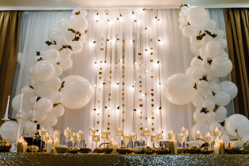 Table setting for wedding. Decorated arch for wedding ceremony. White balloons, candles, autumn leaves and small pumpkins. Autumn location and Halloween decor.