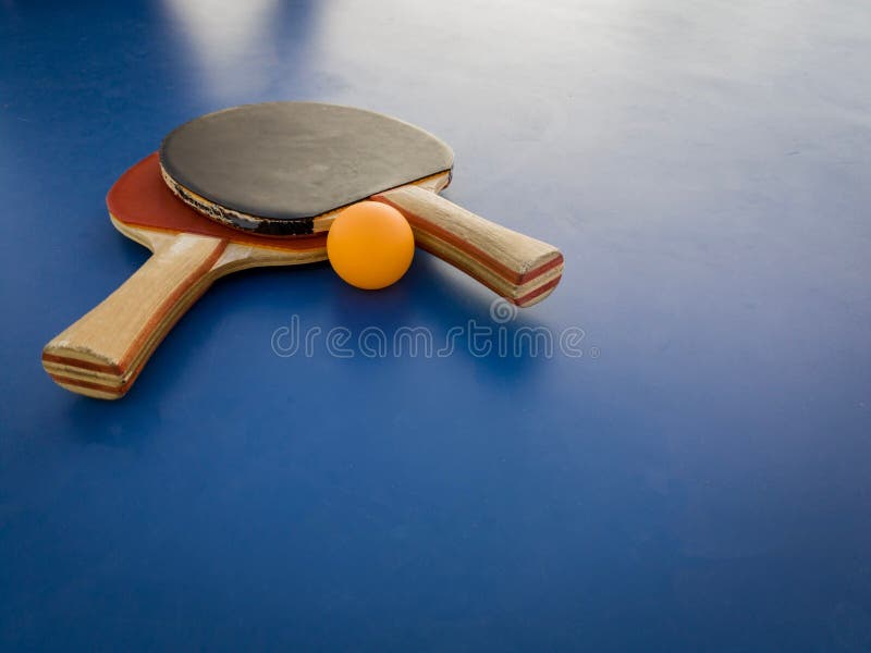 A Table Tennis Racket and Ball Resting on a Blue Surface Stock Photo