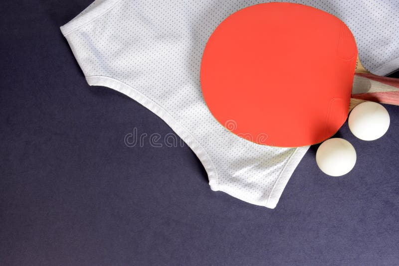 Table tennis rackets, sports shirt and balls on a dark background