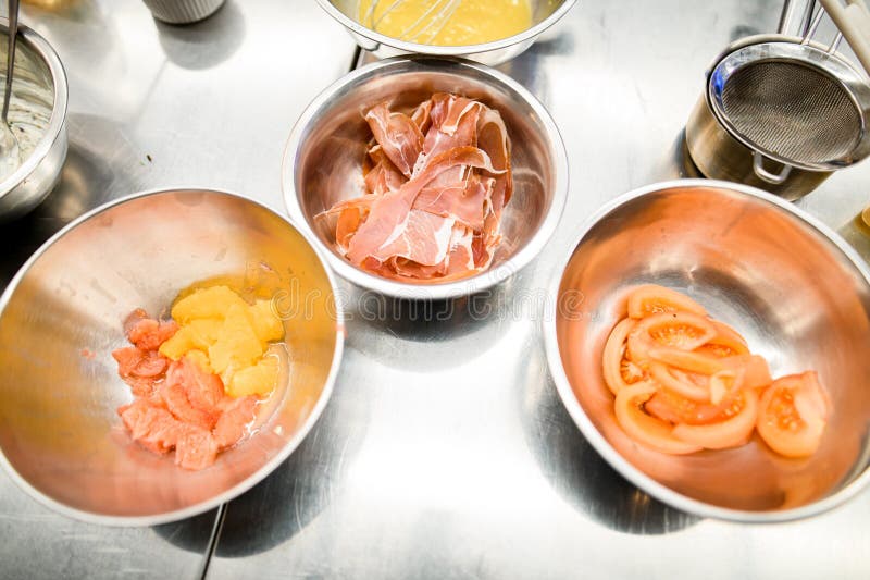 Table with three separated bowls with cutted jamon,grapefruit, orange and tomatoes. Salad ingridiends. Spanish cuisine.