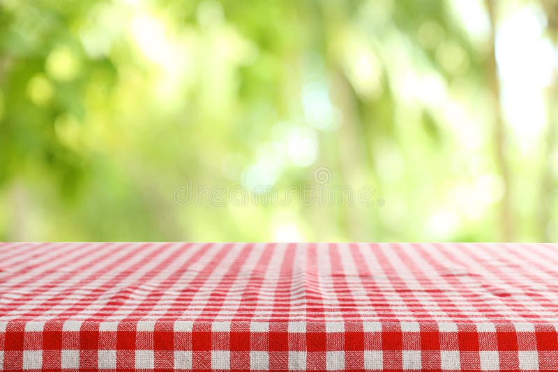 Table vide avec la serviette rouge à carreaux sur le fond brouillé vert photos stock Table vide avec la serviette rouge à carreaux sur le fond brouillé vert photos stock