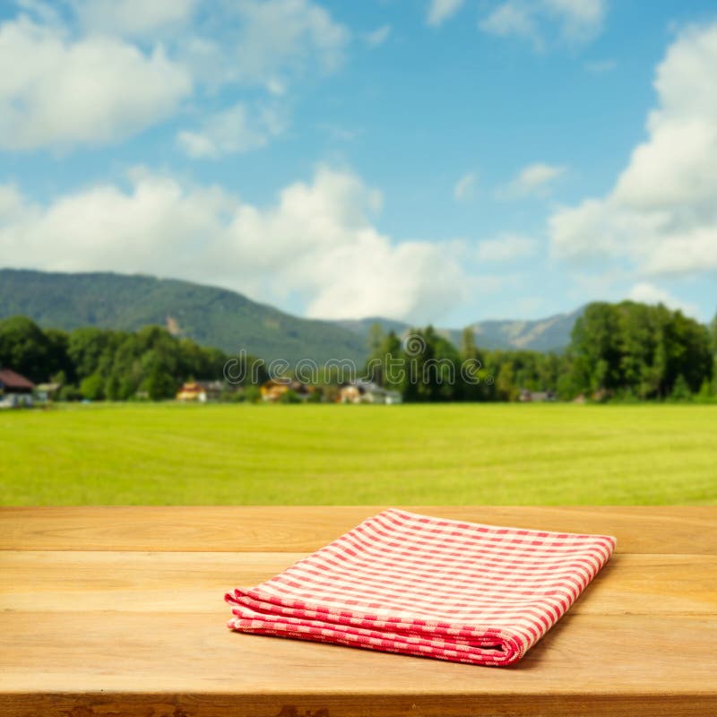 Empty table covered with checked tablecloth over beautiful green landscape. Empty table covered with checked tablecloth over beautiful green landscape