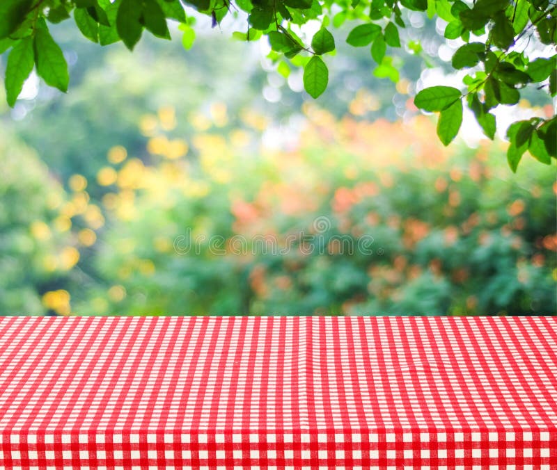 Empty table and red tablecloth with blur green leaves bokeh background, for product display montage. Empty table and red tablecloth with blur green leaves bokeh background, for product display montage