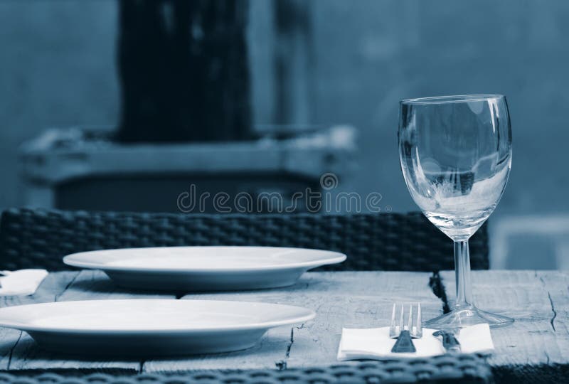 Table with wineglass and dinner plates in a garden