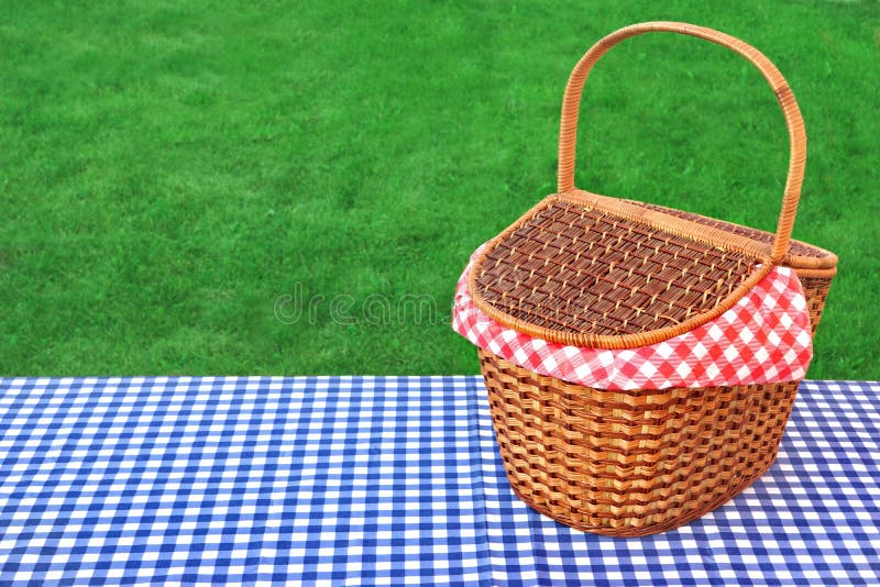 Outdoor Rustic Picnic Table With Hamper And Blue Checkered Tablecloth On The Lawn In The Park Rest Area. Breaking Concept. Outdoor Rustic Picnic Table With Hamper And Blue Checkered Tablecloth On The Lawn In The Park Rest Area. Breaking Concept