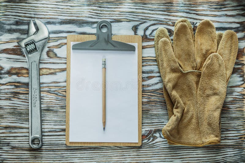 Tablero del lápiz de la llave inglesa ajustable de los guantes protectores en de madera imagen de archivo