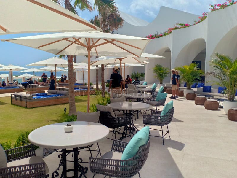 Kuta, Indonesia - 15th October 2019; Tables, chairs, and white umbrellas on a Cafe Del Mar Bali beach club on sunny day. Kuta, Indonesia - 15th October 2019; Tables, chairs, and white umbrellas on a Cafe Del Mar Bali beach club on sunny day