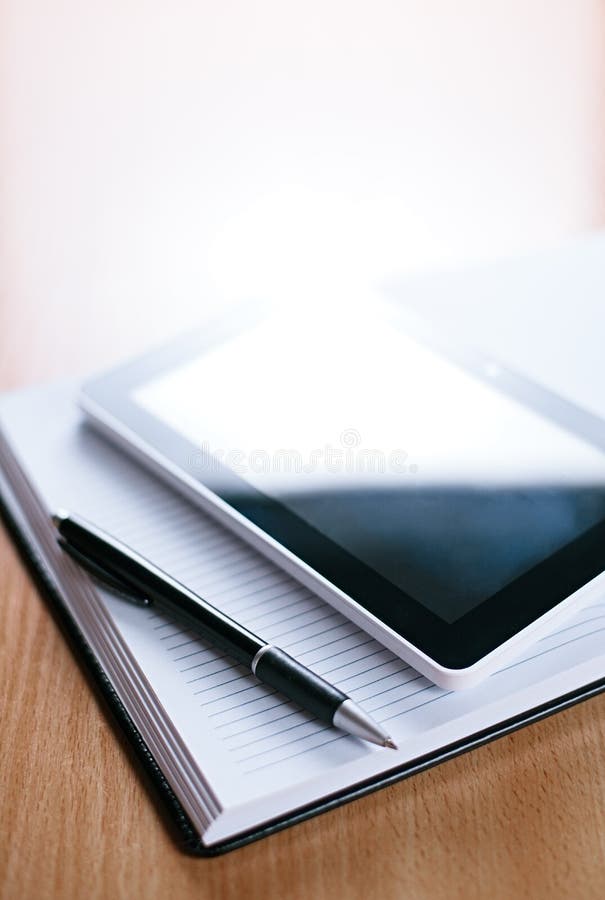 Tablet Gadget Above Notebook with Pen on Table.