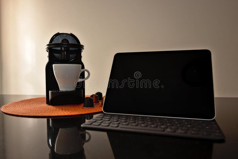 Tablet on a Granite Counter Next To a Coffee Pot and Coffee Capsules