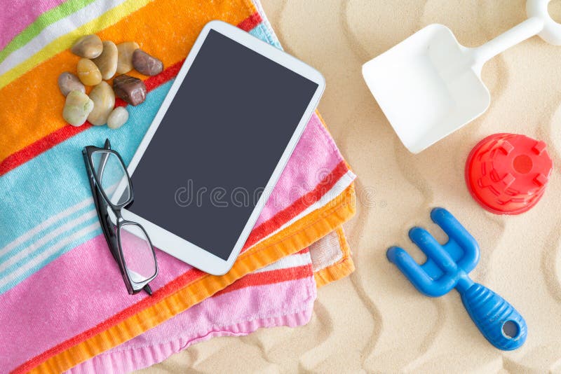 Tablet-pc on a beach towel with glasses and toys