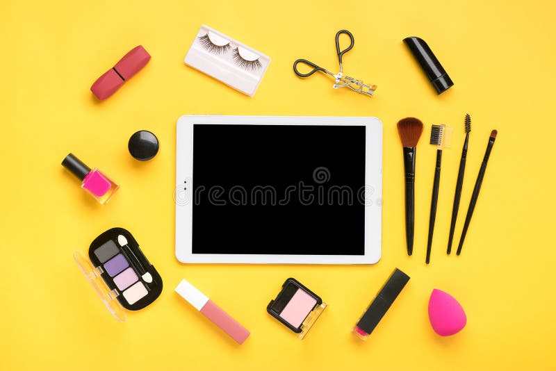 Tablet, set of professional decorative cosmetics, makeup tools and accessory of trendy pink color isolated on yellow background Beauty, fashion, party, shopping concept Flat lay composition Mock up