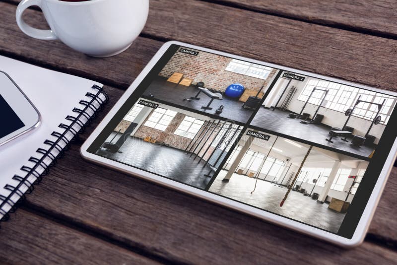 Tablet with View of Gym from Security Cameras on Screen Lying on Wooden