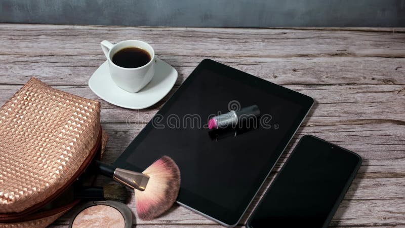 Tablet με ένα κραγιόν πάνω του, περιτριγυρισμένο από ένα καπνιστό φλασκί καφέ smartphone και τσάντα για μακιγιάζ