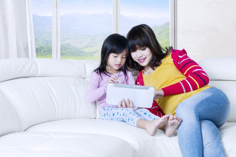 Tableta bonita del uso de la mujer y del niño en casa imágenes de archivo libres de regalías Tableta bonita del uso de la mujer y del niño en casa imágenes de archivo libres de regalías