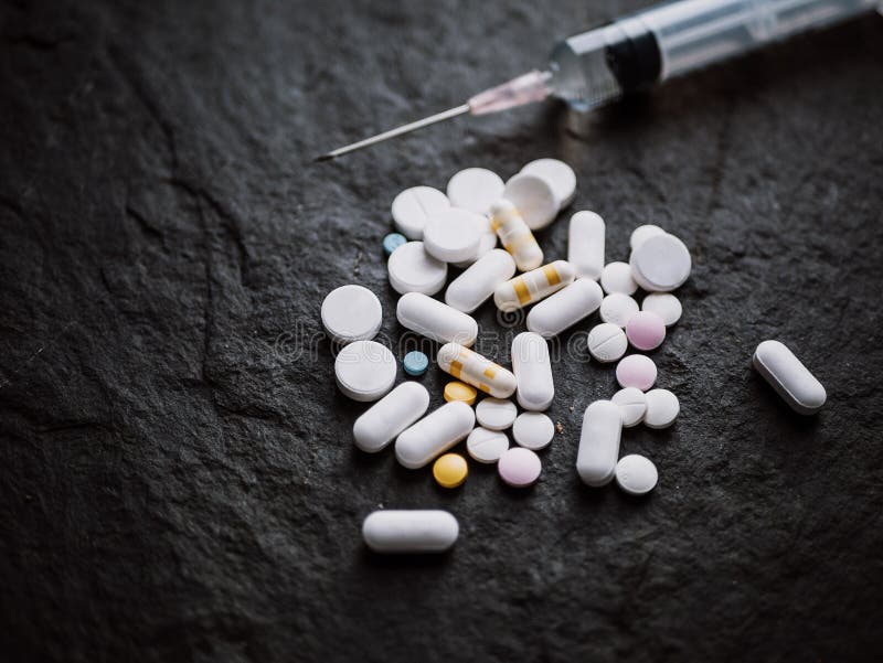 Tabletas y cápsulas farmacéuticas coloridas clasificadas de las píldoras de la medicina con la aguja de la inyección de la jering