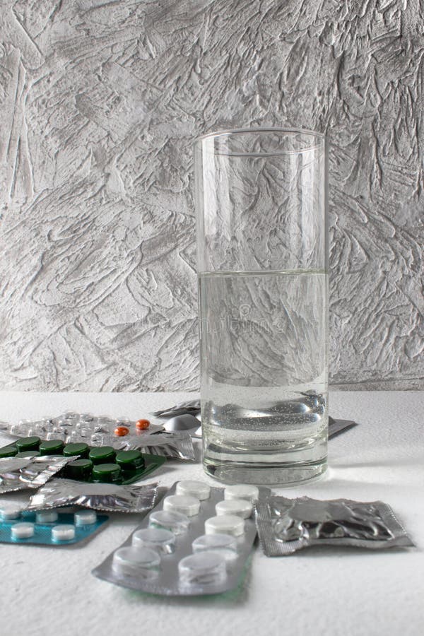 Tabletten in pakken op een witte achtergrond dichtbij een glas water Pillen stock foto Tabletten in pakken op een witte achtergrond dichtbij een glas water Pillen stock foto