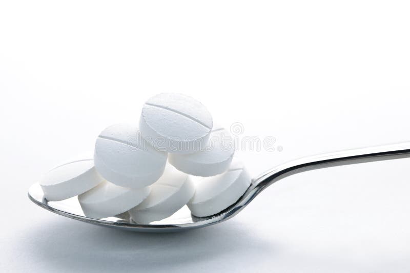 Calcium supplement pills piled on metal spoon closeup. Calcium supplement pills piled on metal spoon closeup