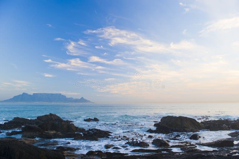 Table Mountain - the world famous landmark in Cape Town, South Africa. Picture taken on a clear Winters day from the Blouberg Strand beach. A vivid blue sky looks spectacular behind clouds in the sunset. Table Mountain - the world famous landmark in Cape Town, South Africa. Picture taken on a clear Winters day from the Blouberg Strand beach. A vivid blue sky looks spectacular behind clouds in the sunset.