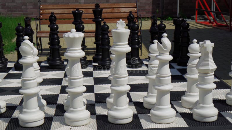 Um jogo de esportes um grande tabuleiro de xadrez e peças de plástico  close-up de grandes peças brancas e um xadrez gigante