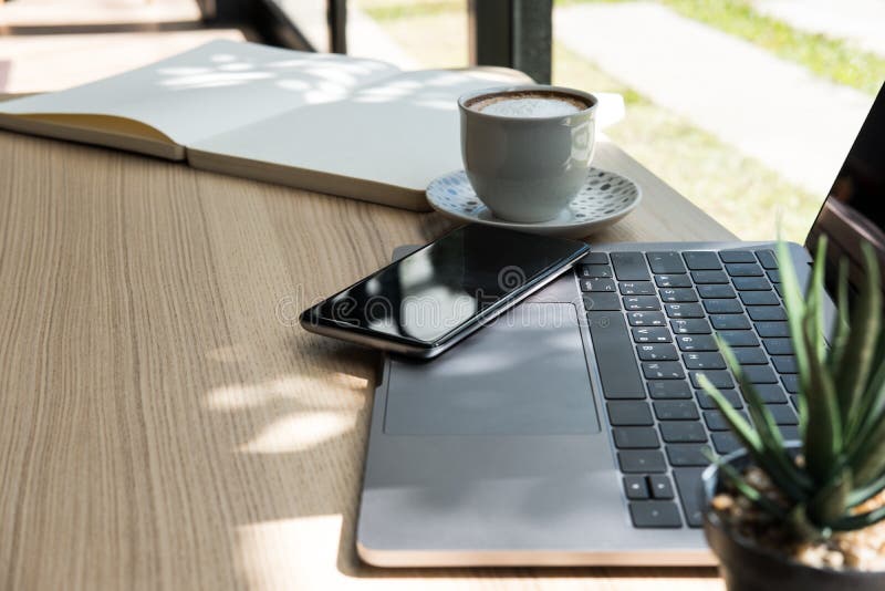 Taccuino del computer, smartphone sullo scrittorio di legno computer portatile, tazza di caffè a fotografia stock