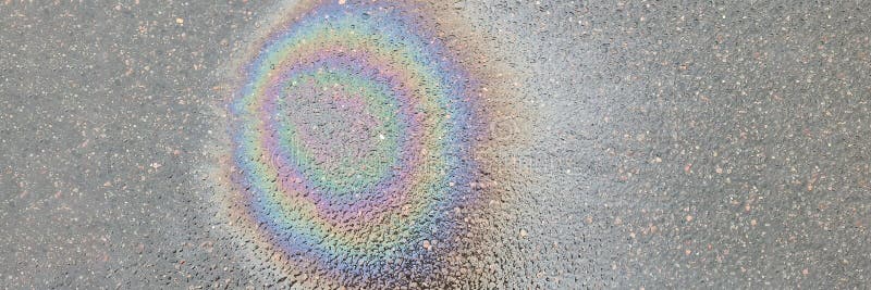 Tache arc-en-ciel sur l'asphalte humide à partir de l'huile machine fond. concept de protection environnementale