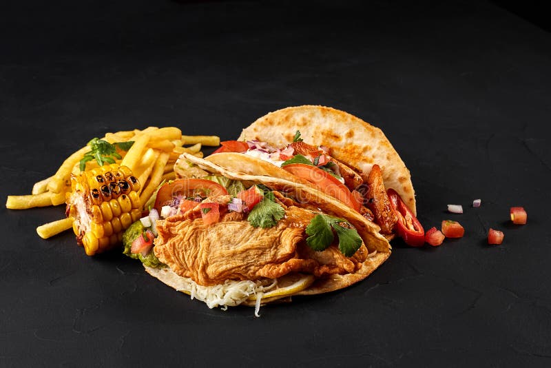 Taci con il pollo, pomodoro e ortaggi freschi e salsa di tartaro su fondo nero fotografie stock Taci con il pollo, pomodoro e ortaggi freschi e salsa di tartaro su fondo nero fotografie stock