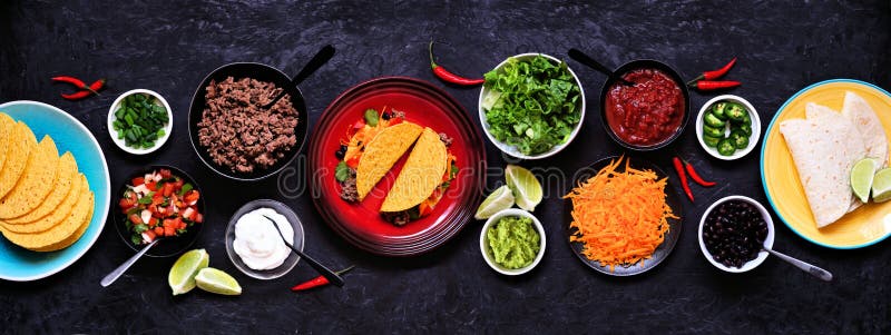 Taco bar table scene with a selection of ingredients. Top view on a dark slate banner background. Mexican food buffet. Taco bar table scene with a selection of ingredients. Top view on a dark slate banner background. Mexican food buffet