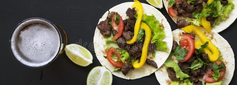 Tacos savoureux avec du boeuf et légumes, bière et chaux sur une surface noire, vue aérienne Cuisine mexicaine Configuration plat images libres de droits Tacos savoureux avec du boeuf et légumes, bière et chaux sur une surface noire, vue aérienne Cuisine mexicaine Configuration plat images libres de droits