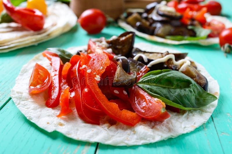 Tacos végétarien avec l'aubergine, tomates-cerises, poivrons doux sur un fond en bois lumineux image libre de droits Tacos végétarien avec l'aubergine, tomates-cerises, poivrons doux sur un fond en bois lumineux image libre de droits