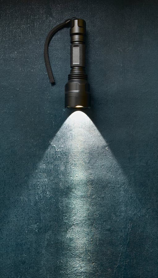 Tactical flashlight shines with bright beam on grunge dark blue background royalty free stock photos