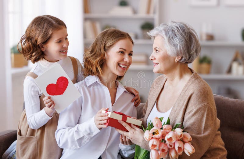 Tag der glücklichen internationalen Frauen. Tochter und Enkelin, die Großmutter Blumen schenken, feiern den Tag der Mütter stockfoto