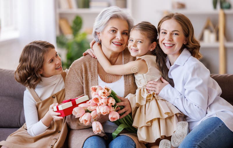Tag der glücklichen internationalen Frauen. Tochter und Enkelin, die Großmutter Blumen schenken, feiern den Tag der Mütter lizenzfreie stockbilder