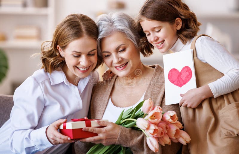Tag der glücklichen internationalen Frauen. Tochter und Enkelin, die Großmutter Blumen schenken, feiern den Tag der Mütter stockfoto