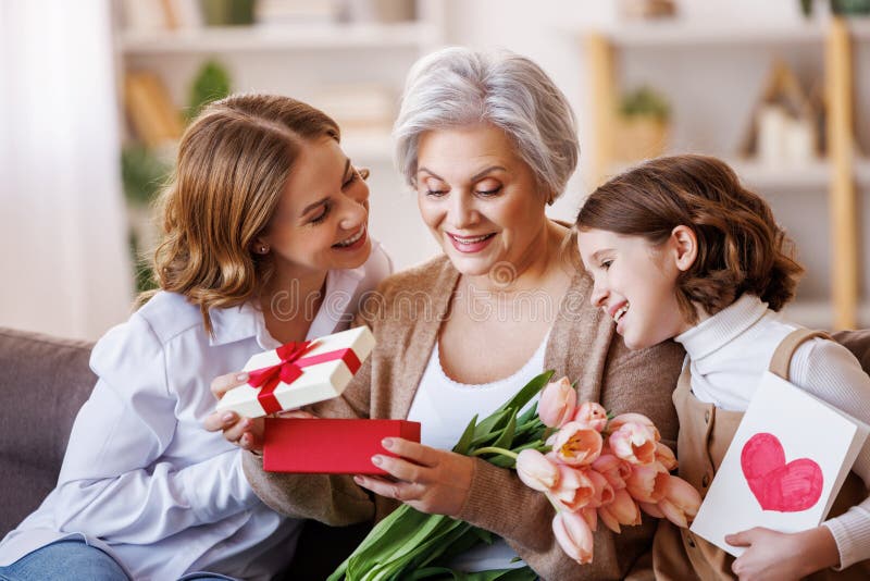 Tag der glücklichen internationalen Frauen. Tochter und Enkelin, die Großmutter Blumen schenken, feiern den Tag der Mütter stockbilder