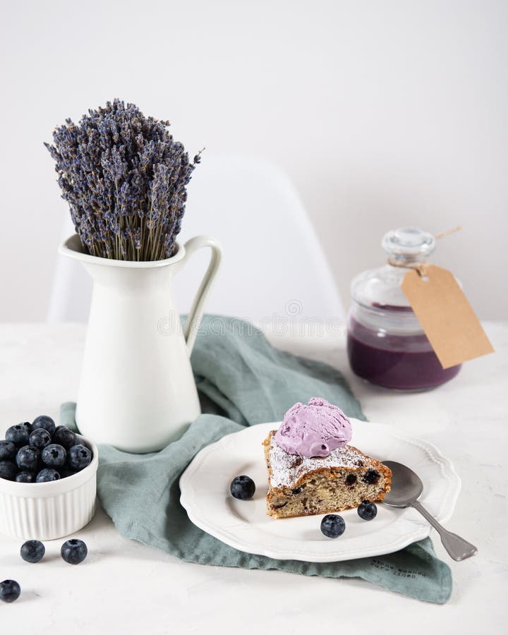 Tagli del dolce casalingo del mirtillo con la palla del gelato, dell'inceppamento del mirtillo in barattolo e del mazzo della lav fotografia stock Tagli del dolce casalingo del mirtillo con la palla del gelato, dell'inceppamento del mirtillo in barattolo e del mazzo della lav fotografia stock