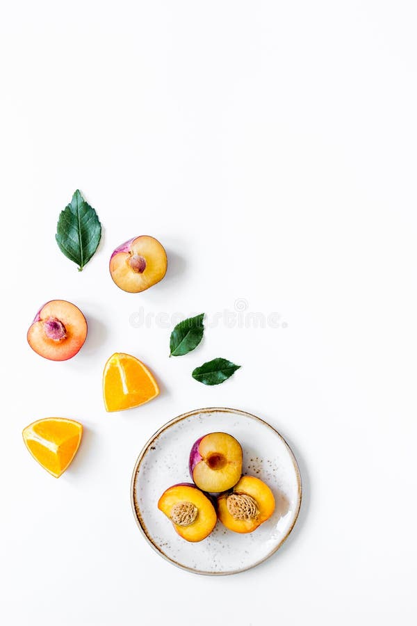 Tagli la pesca e l'arancia per frutta esotica sul modello bianco di vista superiore del fondo dei piatti immagini stock Tagli la pesca e l'arancia per frutta esotica sul modello bianco di vista superiore del fondo dei piatti immagini stock