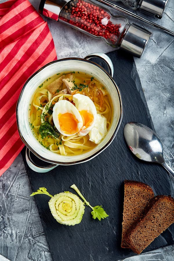 Tagliatelle appetitose in un brodo di pollo con l'uovo sodo immagine stock Tagliatelle appetitose in un brodo di pollo con l'uovo sodo immagine stock