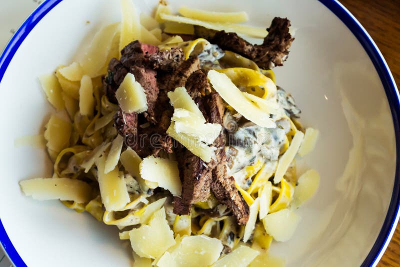 Pasta tagliatelle with beef and parmesan on top in a white plate. Pasta tagliatelle with beef and parmesan on top in a white plate