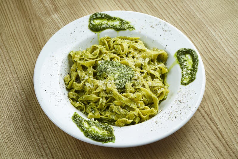 tagliatelle de pasta tradicional italiana con salsa de pesto y parmesano en un plato blanco sobre fondo de madera Cerrar vista Al foto de archivo tagliatelle de pasta tradicional italiana con salsa de pesto y parmesano en un plato blanco sobre fondo de madera Cerrar vista Al foto de archivo