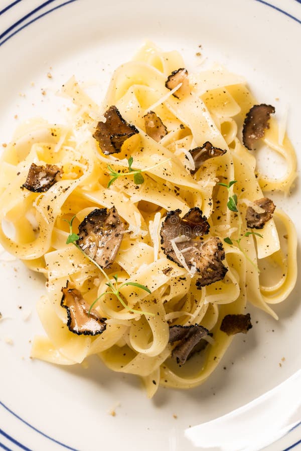 Tagliatelle pasta with black truffles and parmesan cheese - close up macro. Plate captured from above top view, flat lay