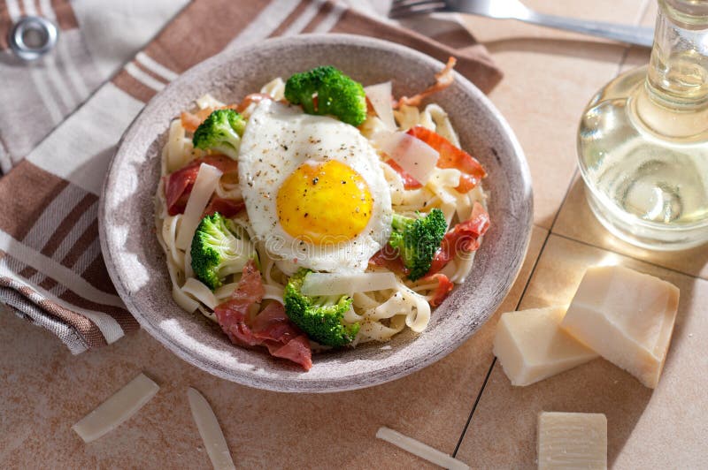 Tagliatelle Pasta with Broccoli, Prosciutto and Fried Egg. Stock Photo