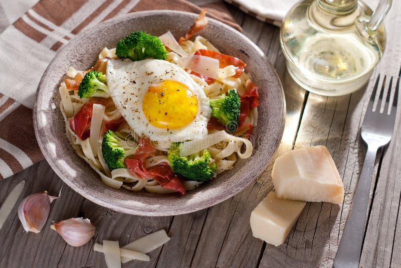 Tagliatelle Pasta with Broccoli, Prosciutto and Fried Egg. Stock Photo