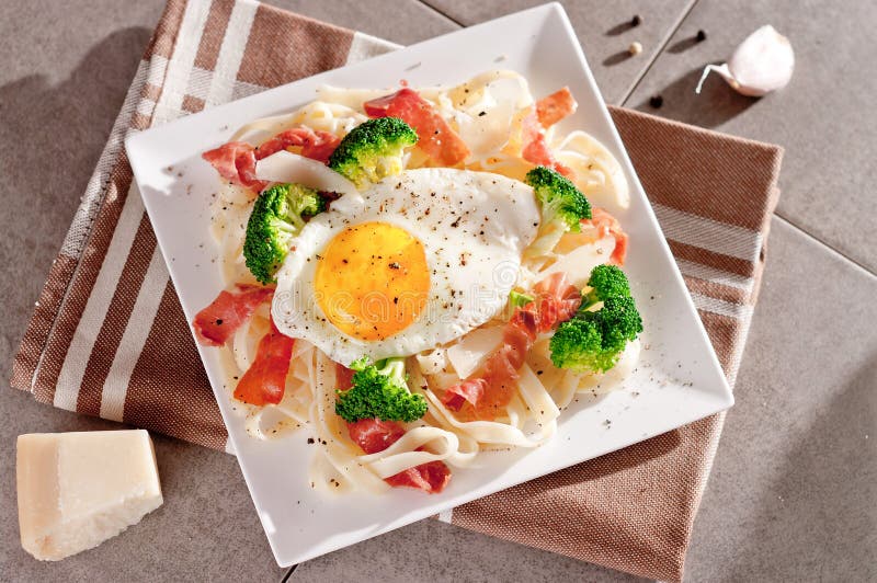 Tagliatelle Pasta with Broccoli, Prosciutto and Fried Egg. Stock Photo