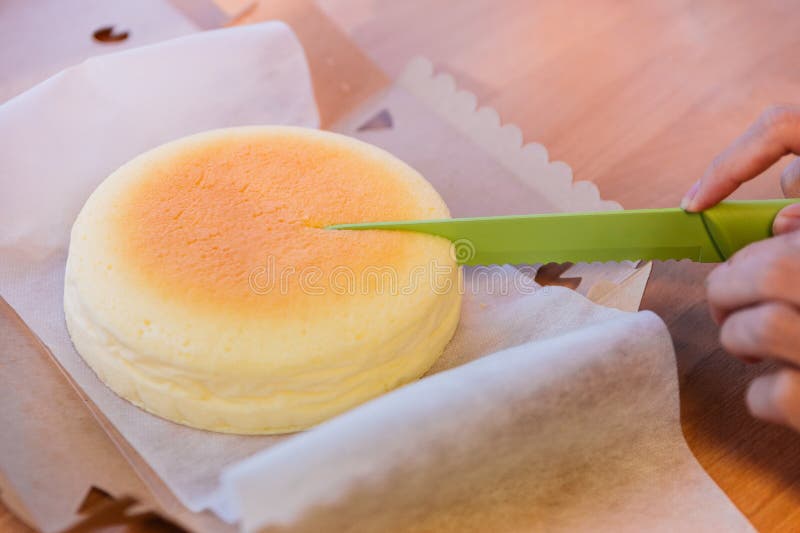 Taglio giapponese della torta di formaggio dal coltello verde in scatola di carta aperta Morbido e dolce immagini stock libere da diritti Taglio giapponese della torta di formaggio dal coltello verde in scatola di carta aperta Morbido e dolce immagini stock libere da diritti