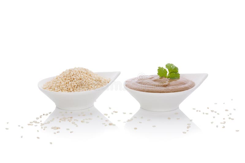 Tahini dip and sesame seeds in white bowls on white background. African and middle eastern traditional cuisine. Tahini dip and sesame seeds in white bowls on white background. African and middle eastern traditional cuisine.