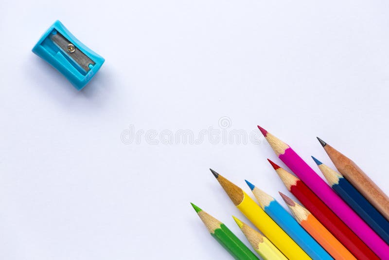 Taille-crayons et beaucoup de crayons sur le fond de livre blanc photographie stock libre de droits Taille-crayons et beaucoup de crayons sur le fond de livre blanc photographie stock libre de droits