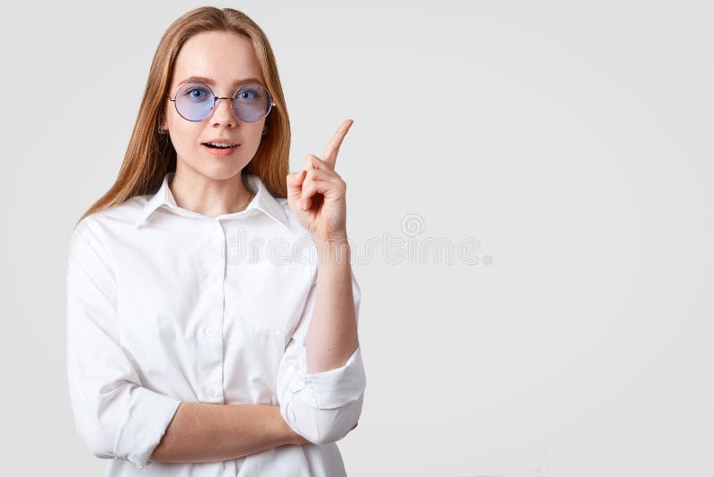Taille herauf Schuss der hübschen Frau in den blauen Schatten, Showrichtung mit dem Zeigefinger, kleidete im zufälligen weißen T- lizenzfreies stockbild Taille herauf Schuss der hübschen Frau in den blauen Schatten, Showrichtung mit dem Zeigefinger, kleidete im zufälligen weißen T- lizenzfreies stockbild