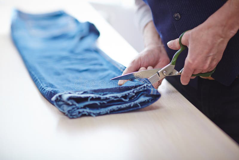 tailor repairing clothes closeup man cutting jeans pants tailors table atelier 93960706