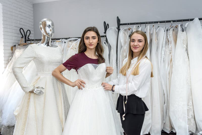 Tailor in Wedding Salon Helping Bride To Try on Dress Stock Photo ...