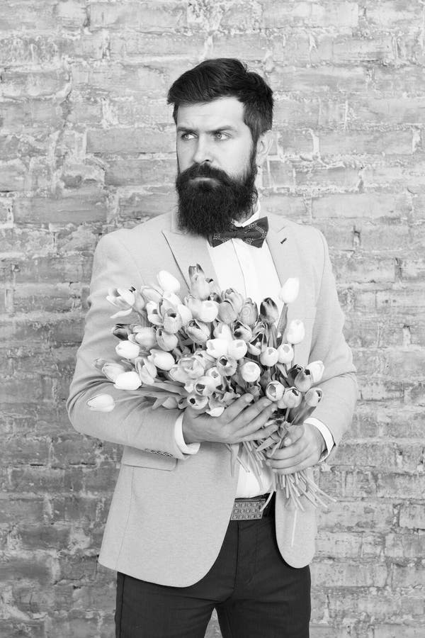 We take flowers personally. Spring gift. Bearded man hipster with flowers. Love. international holiday. Womens day stock photo We take flowers personally. Spring gift. Bearded man hipster with flowers. Love. international holiday. Womens day stock photo